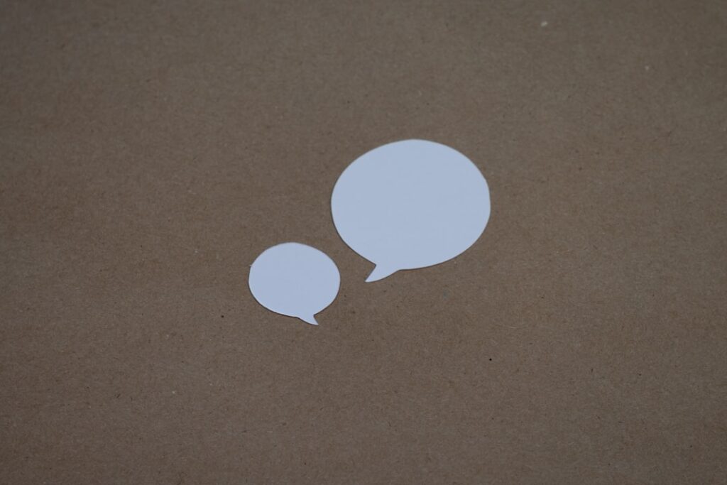 two white speech bubbles sitting on top of a brown surface